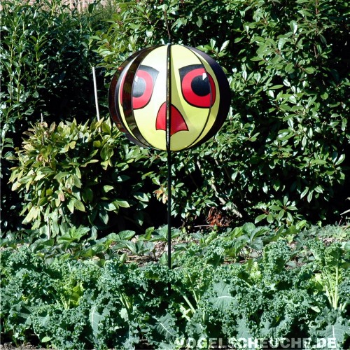 Windrotor TURBINE in Gelb-Rot auf einer Stange über einem Gemüsebeet mit Grünkohl.